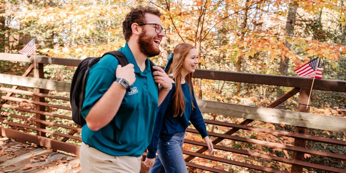 Students smiling and laughing while walking across bridge.